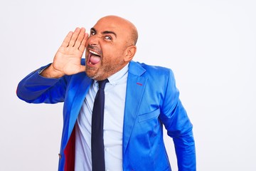 Middle age businessman wearing suit standing over isolated white background shouting and screaming loud to side with hand on mouth. Communication concept.