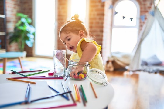 Beautiful toddler standing playing with chocolate colored balls on the table at kindergarten