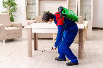 Young contractor doing pest control at home