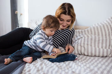 Mother reading a book to her son in bed. 