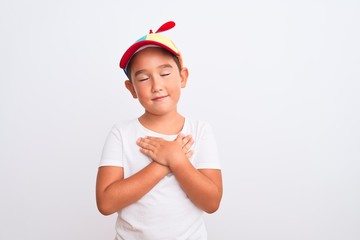 Beautiful kid boy wearing fanny colorful cap with propeller over isolated white background smiling...