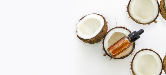 Top view of cracked Coconuts with Coconut essential oil in eyedropper isolated on white