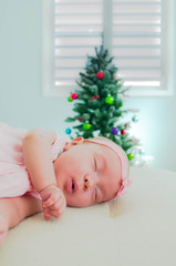 Baby sleeping in front of the christmas tree