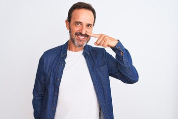 Middle age handsome man wearing blue denim shirt standing over isolated white background Pointing with hand finger to face and nose, smiling cheerful. Beauty concept