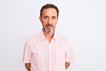 Middle age handsome man wearing casual pink shirt standing over isolated white background with...