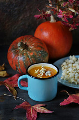 pumpkin soup with popcorn  in an enamel mug on a dark background.