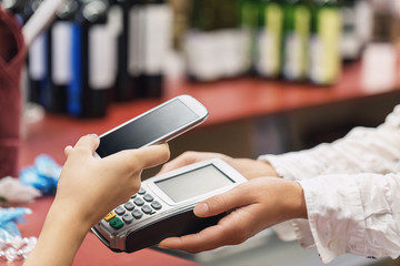 The buyer pays for the item at the cash register using a smartphone. Contactless payment process in the supermarket