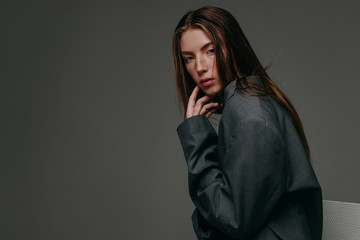 Young girl in trench coat with hat on gray background