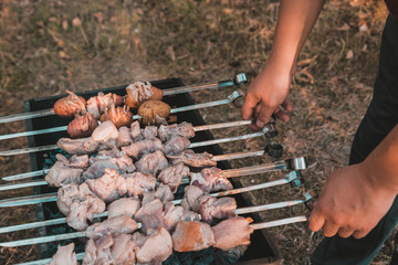 Man frying shish kebab on the grill. Hands closeup outdoors