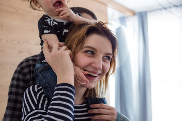 Fototapeta premium Mother giving her baby a piggyback ride around the house.