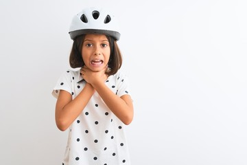 Beautiful child girl wearing security bike helmet standing over isolated white background shouting and suffocate because painful strangle. Health problem. Asphyxiate and suicide concept.