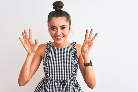 Beautiful woman with bun wearing casual dresss standing over isolated white background showing and pointing up with fingers number eight while smiling confident and happy.