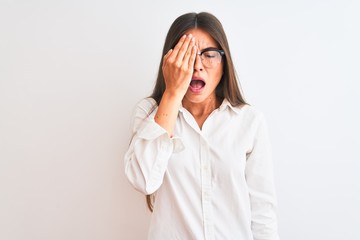 Young beautiful businesswoman wearing glasses standing over isolated white background Yawning tired covering half face, eye and mouth with hand. Face hurts in pain.