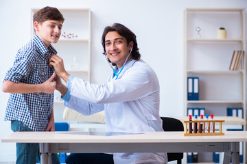 Male doctor examining boy by stethoscope