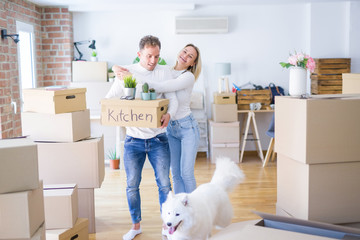 Young beautiful couple with dog moving cardboard boxes at new home