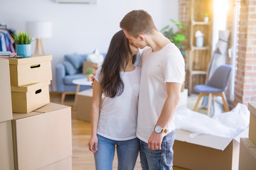 Fototapeta na wymiar Young beautiful couple standing at new home around cardboard boxes