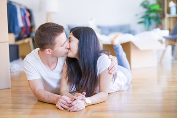 Young beautiful couple lying down at new home around cardboard boxes