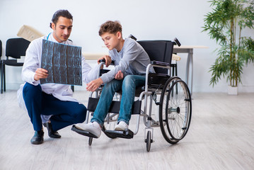 Young male doctor pediatrist and boy in wheel-chair