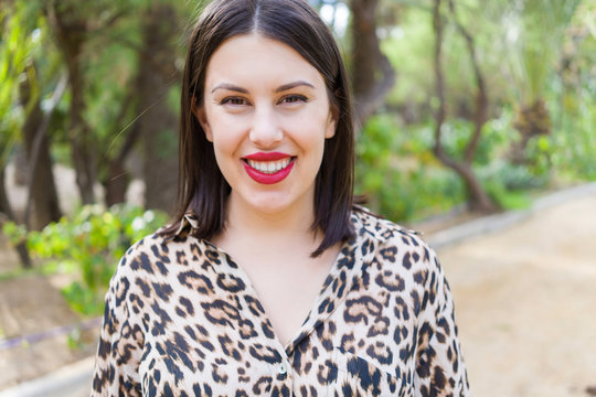 Young beautiful woman with red lips smiling happy at garden