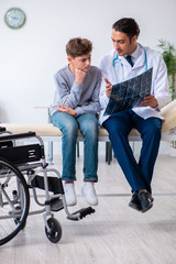 Obraz na płótnie Canvas Young male doctor pediatrist and boy in wheel-chair
