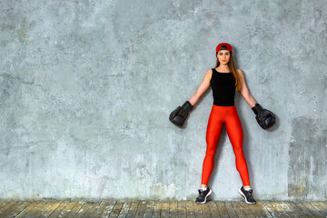 Beautiful athletic girl posing in pink boxing gloves on a gray background. Copy space. Concept sport, fight, goal achievement.