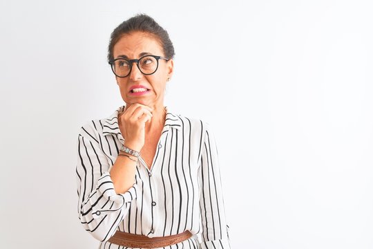 Middle age businesswoman wearing striped dress and glasses over isolated white background Thinking worried about a question, concerned and nervous with hand on chin