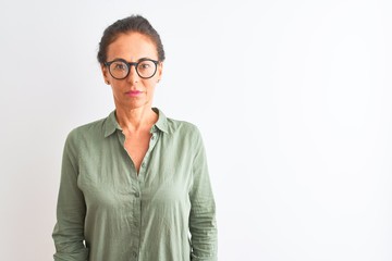 Middle age woman wearing green shirt and glasses standing over isolated white background with...
