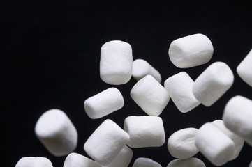 falling marshmallows frozen in the air on a black background for design