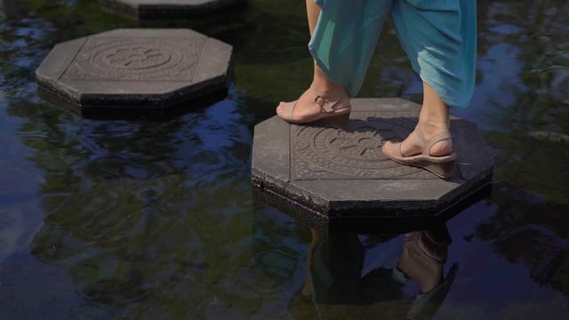 Slowmotion shot of a young woman tourist visiting the Tirta Gangga water palace, former royal palace on the Bali Island, Indonesia