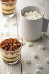 Tiramisu two glasses with marshmallows and a cup of coffee on a light wooden background