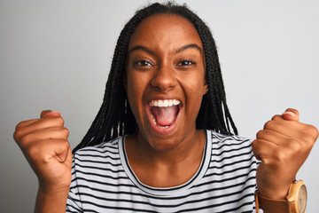 Young african american woman wearing striped t-shirt standing over isolated white background screaming proud and celebrating victory and success very excited, cheering emotion