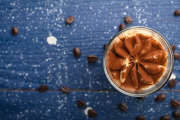 flat lay, Tiramisu two glasses with coffee grains on a blue wooden background. With space for design