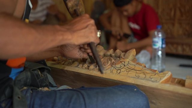 Slowmotion closeup shot of a master craftsman doing traditional wood carving