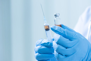 Fototapeta premium Close up doctor's hand holding medicine bottle and syringe for vaccine to patient on blue tone.Nurse using syringe are vaccination to patient for influenza protection.Medication treatment concept.