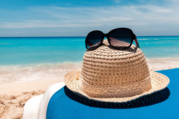 Summer straw hat and sunglasses on theblue chair at the beach