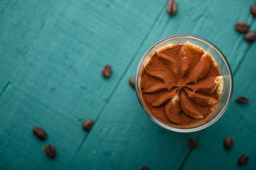 flat lay, Tiramisu two glasses with grains of coffee on a green wooden background.