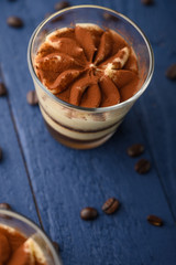 Tiramisu two glasses with coffee grains on a blue wooden background.Vertical photo