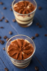 Tiramisu two glasses with coffee grains on a blue wooden background.Vertical photo