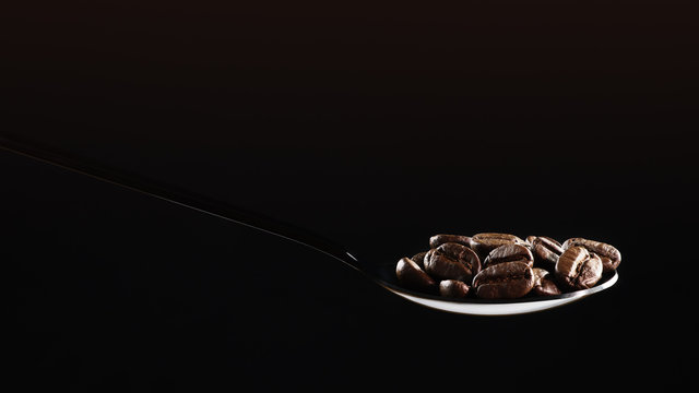 beverage background of roasted coffee beans in spoon isolated on dark background