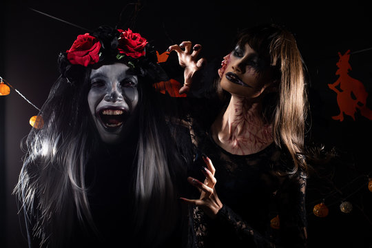 Devil White face clown and Zombie girl black hair, two ghosts possessed together over Halloween backgrounds with witches and pumpkins head decorate die tree, low key dark shadow exposure copy space