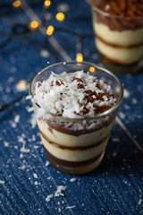 Tiramisu in a glass sprinkled with coconut. On a background of blurry lights
