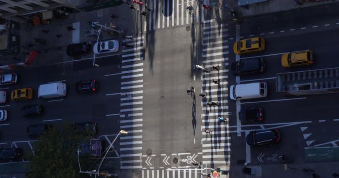 A high angle view of pedestrians and traffic on 6th Avenue in midtown Manhattan.  	