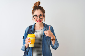 Beautiful redhead student woman drinking take away coffee over isolated white background happy with big smile doing ok sign, thumb up with fingers, excellent sign