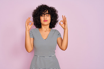Young arab woman with curly hair wearing striped dress over isolated pink background relax and...