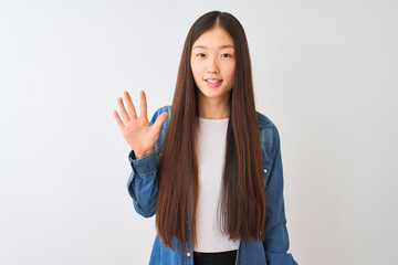 Young chinese woman wearing denim shirt standing over isolated white background showing and pointing up with fingers number five while smiling confident and happy.