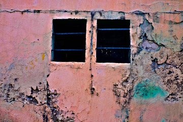 Grungy jouful pink wall with two dark barred windows, love is a prison concept.