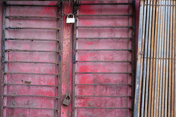Old grungy red door barred and locked with padlocks.