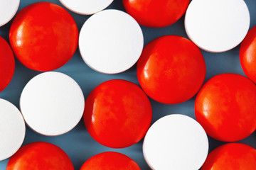 White and red medicine pills on blue background. Close up, top view