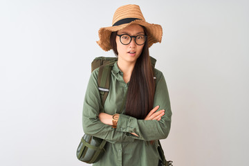 Chinese hiker woman wearing canteen hat glasses backpack over isolated white background skeptic and nervous, disapproving expression on face with crossed arms. Negative person.