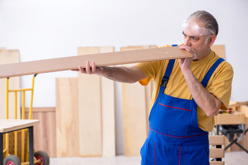 Old male carpenter working in workshop